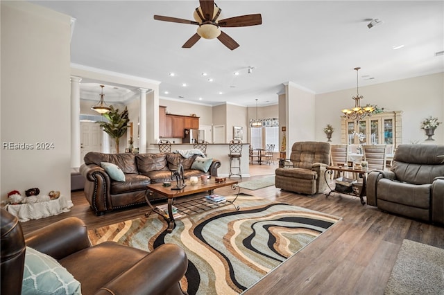 living room with hardwood / wood-style flooring, ornamental molding, ceiling fan with notable chandelier, and ornate columns