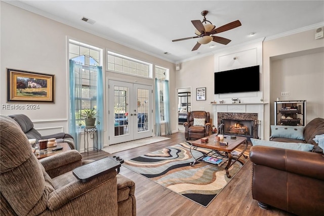 living room featuring french doors, ornamental molding, wood-type flooring, and ceiling fan