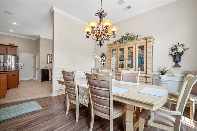 dining room with ornamental molding, an inviting chandelier, and light hardwood / wood-style floors