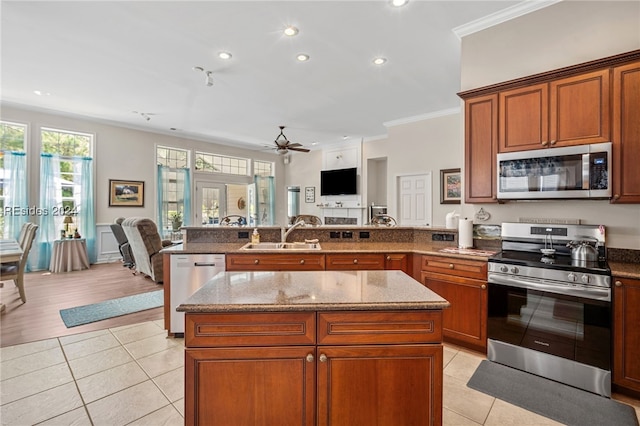 kitchen with sink, stone counters, appliances with stainless steel finishes, ornamental molding, and light tile patterned flooring