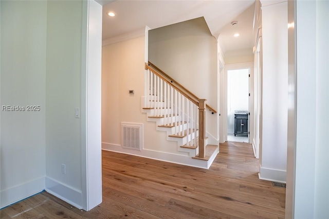 staircase with crown molding and wood-type flooring