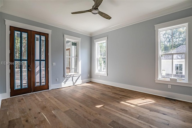 spare room with hardwood / wood-style flooring, crown molding, plenty of natural light, and french doors