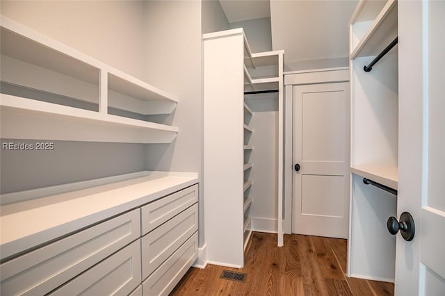 walk in closet with dark hardwood / wood-style floors