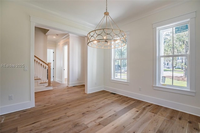 unfurnished dining area with ornamental molding, hardwood / wood-style floors, and a notable chandelier