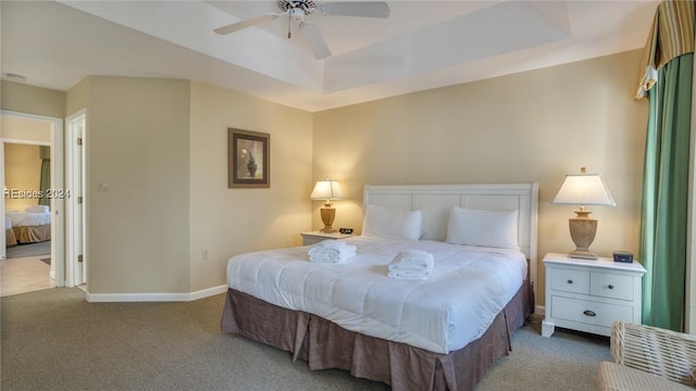 carpeted bedroom featuring a tray ceiling and ceiling fan