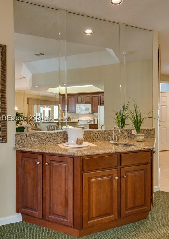 kitchen with light stone counters, sink, and white appliances