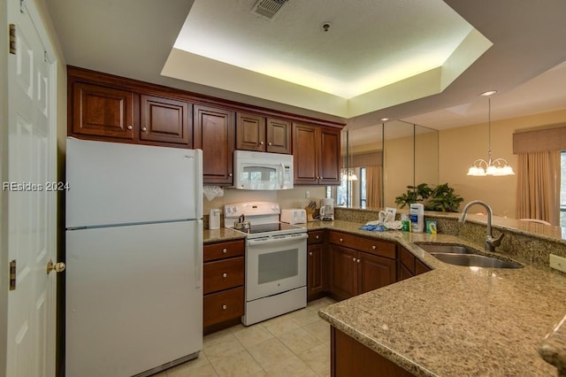 kitchen featuring a tray ceiling, sink, white appliances, and hanging light fixtures