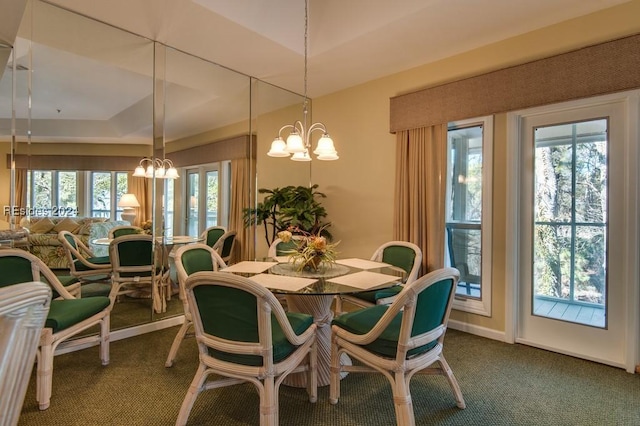 carpeted dining area featuring a raised ceiling, a wealth of natural light, and a chandelier