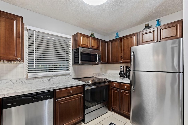 kitchen with decorative backsplash, appliances with stainless steel finishes, a textured ceiling, and light tile patterned floors