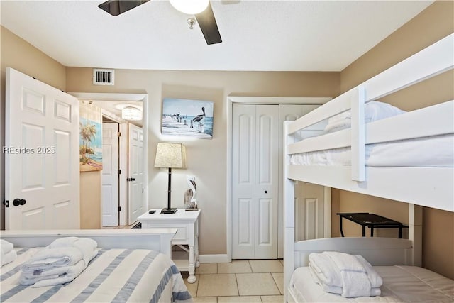 tiled bedroom with ceiling fan and a closet