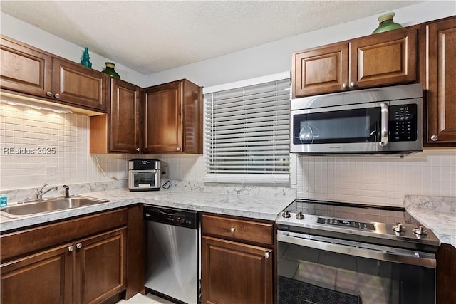 kitchen featuring appliances with stainless steel finishes, sink, backsplash, dark brown cabinetry, and a textured ceiling