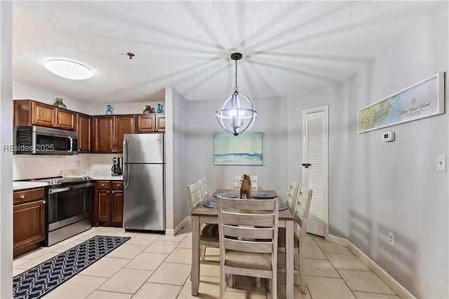 kitchen with light tile patterned floors, appliances with stainless steel finishes, tasteful backsplash, a textured ceiling, and decorative light fixtures