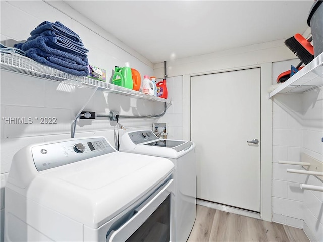 laundry room with independent washer and dryer and light wood-type flooring