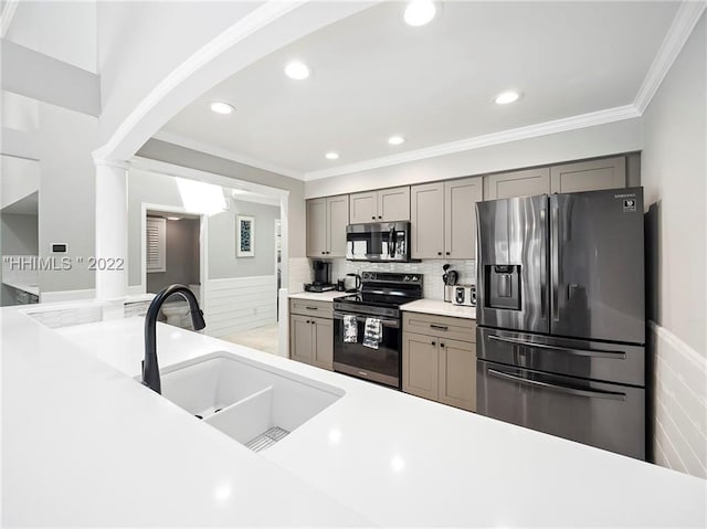 kitchen with gray cabinets, appliances with stainless steel finishes, tasteful backsplash, sink, and ornamental molding