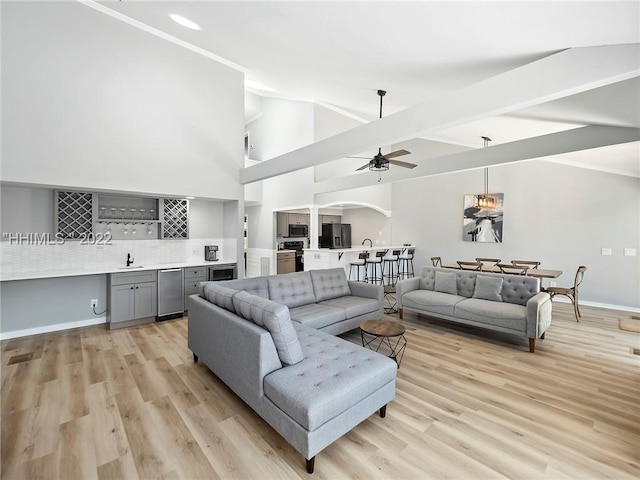 living room with ceiling fan, wet bar, and light wood-type flooring