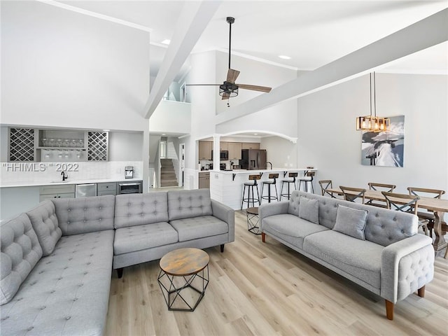 living room with high vaulted ceiling, indoor wet bar, ceiling fan, and light hardwood / wood-style floors