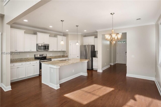 kitchen featuring sink, hanging light fixtures, stainless steel appliances, an island with sink, and white cabinets