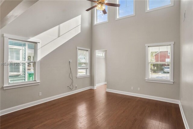 unfurnished living room featuring ceiling fan, a towering ceiling, and dark hardwood / wood-style floors