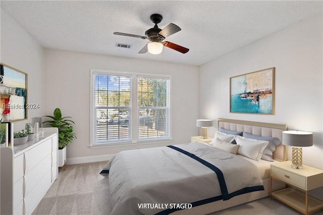 carpeted bedroom with ceiling fan and a textured ceiling