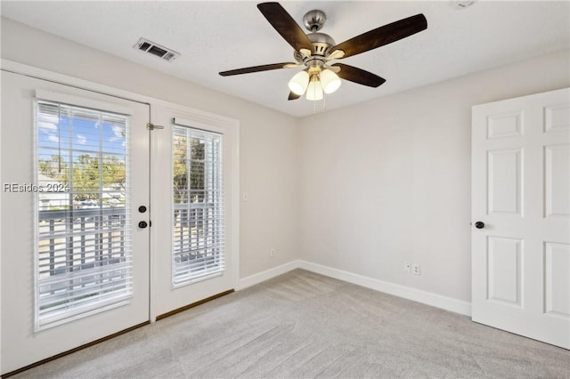 empty room with light colored carpet, french doors, and ceiling fan