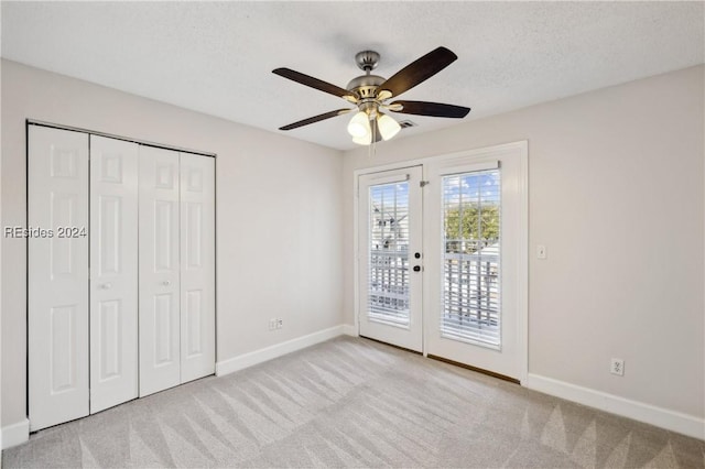 unfurnished bedroom with ceiling fan, a textured ceiling, access to outside, light colored carpet, and a closet