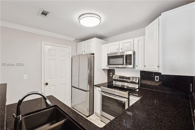 kitchen with sink, crown molding, appliances with stainless steel finishes, white cabinetry, and dark stone counters