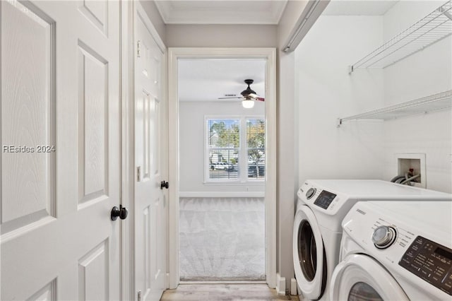 clothes washing area with ornamental molding, washer and clothes dryer, and light colored carpet