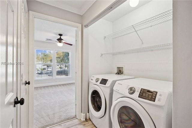 laundry room with ornamental molding, washer and dryer, and light colored carpet