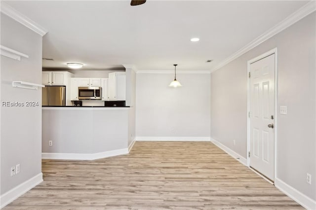 interior space featuring crown molding, appliances with stainless steel finishes, hanging light fixtures, and white cabinets