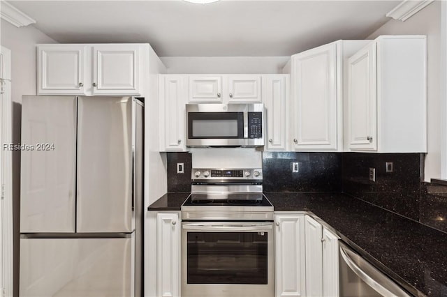 kitchen featuring dark stone countertops, stainless steel appliances, ornamental molding, white cabinets, and decorative backsplash