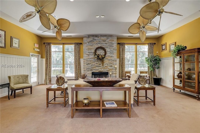 living room with ceiling fan, plenty of natural light, a fireplace, and light colored carpet