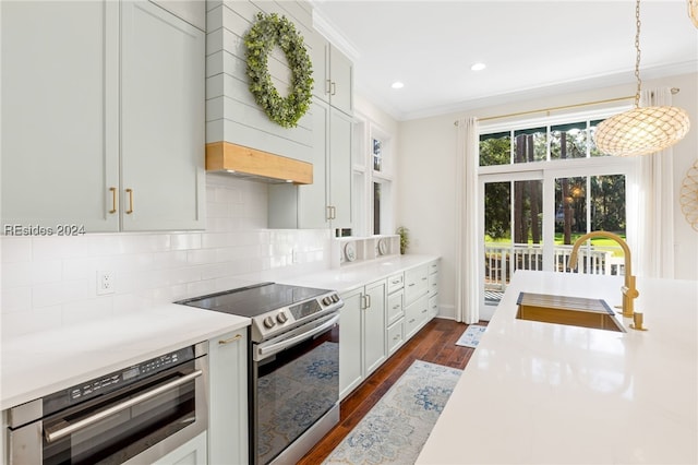 kitchen with sink, dark wood-type flooring, hanging light fixtures, stainless steel appliances, and tasteful backsplash