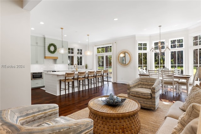 living room with ornamental molding, sink, a chandelier, and dark hardwood / wood-style flooring