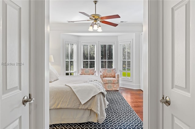 bedroom featuring wood-type flooring, ornamental molding, and ceiling fan