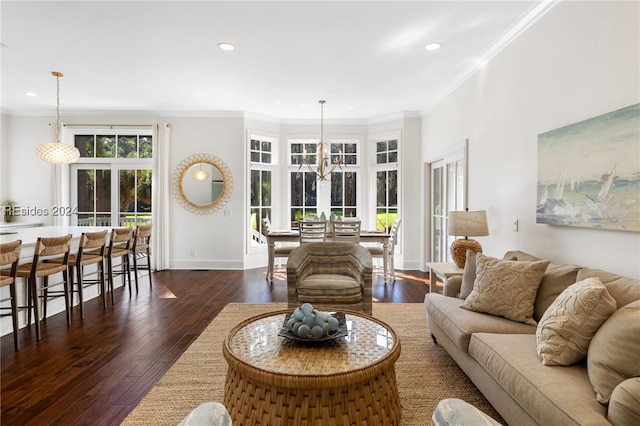 living room with an inviting chandelier, dark wood-type flooring, and ornamental molding