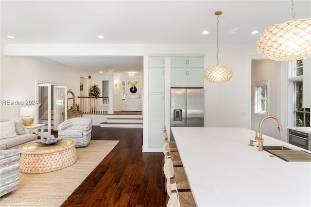 kitchen featuring pendant lighting, sink, dark wood-type flooring, appliances with stainless steel finishes, and ornate columns