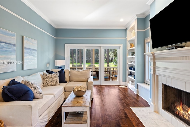 living room with hardwood / wood-style floors, built in shelves, a fireplace, and ornamental molding