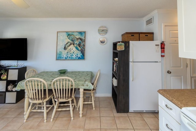 kitchen featuring light tile patterned flooring, white cabinetry, white refrigerator, ornamental molding, and breakfast area