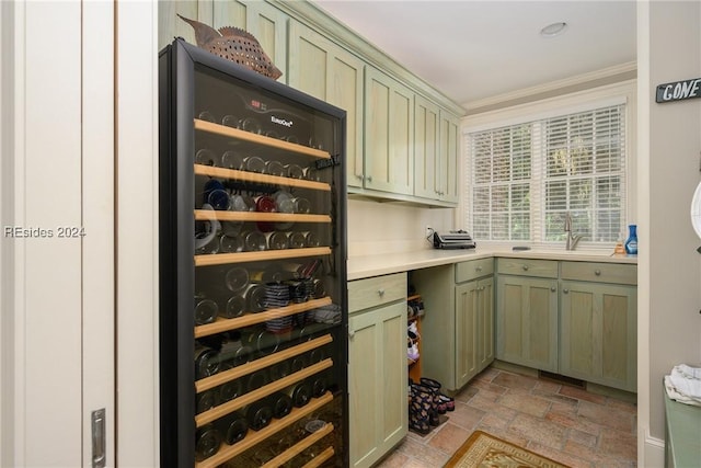 bar featuring sink, crown molding, beverage cooler, and green cabinetry