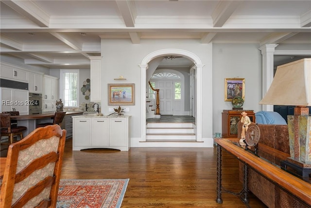 foyer featuring dark hardwood / wood-style flooring, ornamental molding, beamed ceiling, and ornate columns