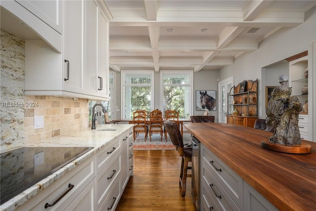 kitchen with white cabinetry, sink, black electric stovetop, and wood counters