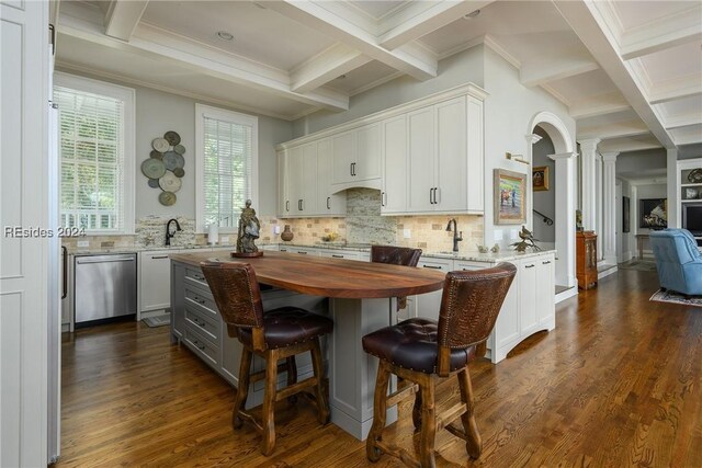 kitchen featuring ornate columns, tasteful backsplash, white cabinets, stainless steel dishwasher, and dark wood-type flooring