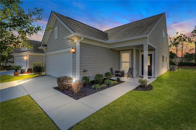 property exterior at dusk featuring a garage, a lawn, and central air condition unit