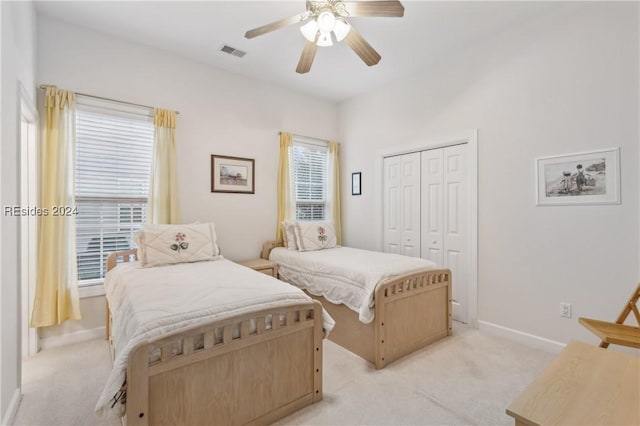 carpeted bedroom with multiple windows, a closet, and ceiling fan