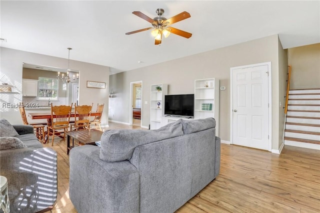 living room featuring ceiling fan with notable chandelier and light hardwood / wood-style floors