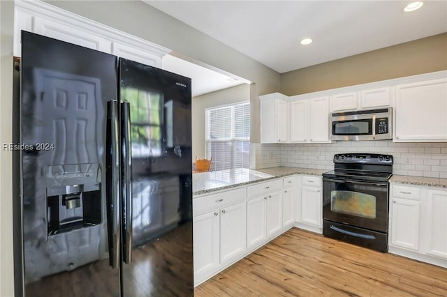 kitchen with tasteful backsplash, white cabinetry, black appliances, light stone countertops, and light wood-type flooring