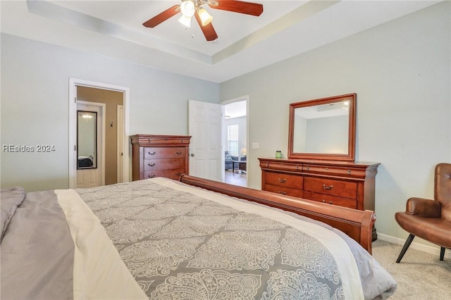 bedroom featuring a raised ceiling, light carpet, and ceiling fan