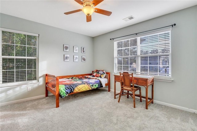 bedroom with ceiling fan, light colored carpet, and multiple windows