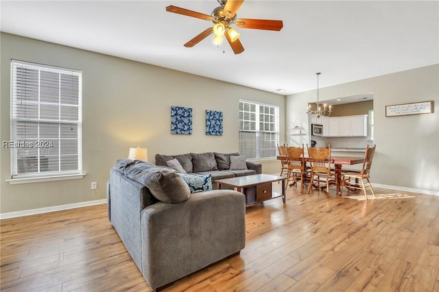 living room featuring ceiling fan with notable chandelier and light hardwood / wood-style floors