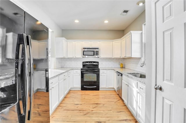 kitchen with light stone countertops, black appliances, sink, and white cabinets